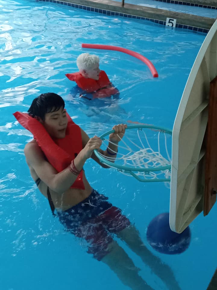 A camper does a slam dunk in the pool